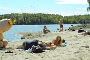 man dressed as giant penis sprays glitter on people at the beach in norway